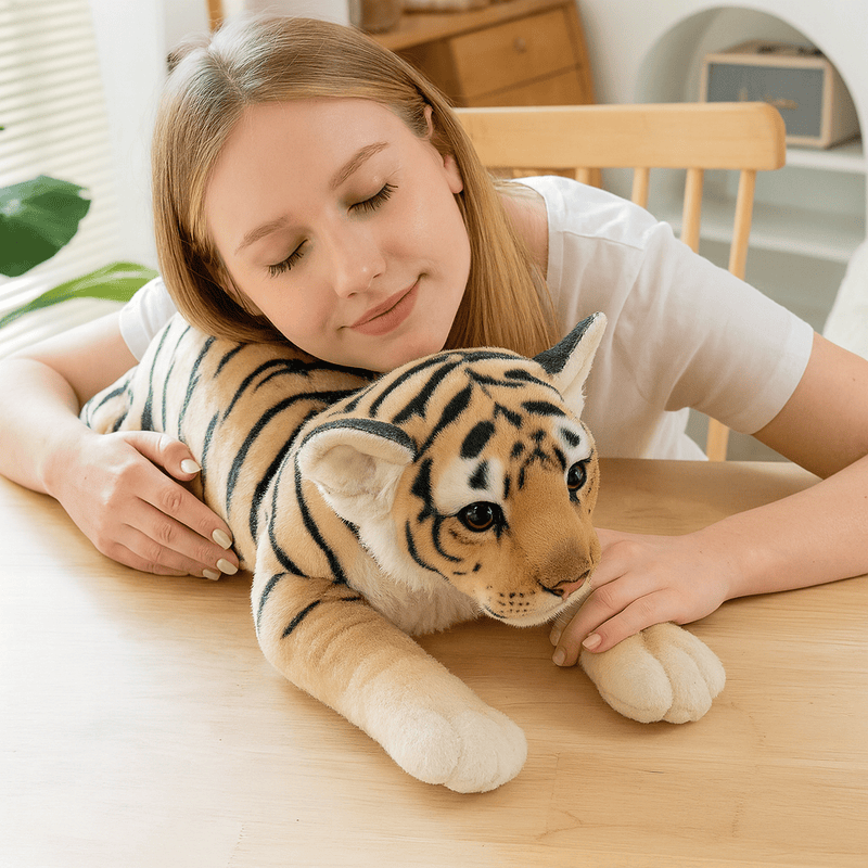 Peluche tigre beige sur une table avec une fille ayant la tête posée dessus Image