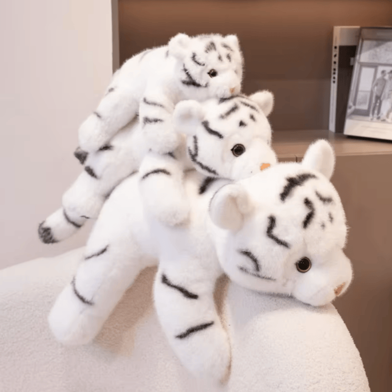 Trois peluches tigres blancs mignons sur une couverture Image