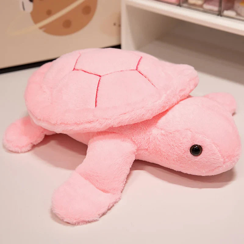 Peluche tortue colorée rose sur un meuble blanc