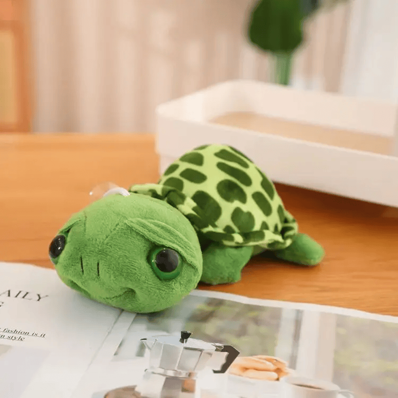 Peluche tortue gros yeux sur une table avec un magazine  Image