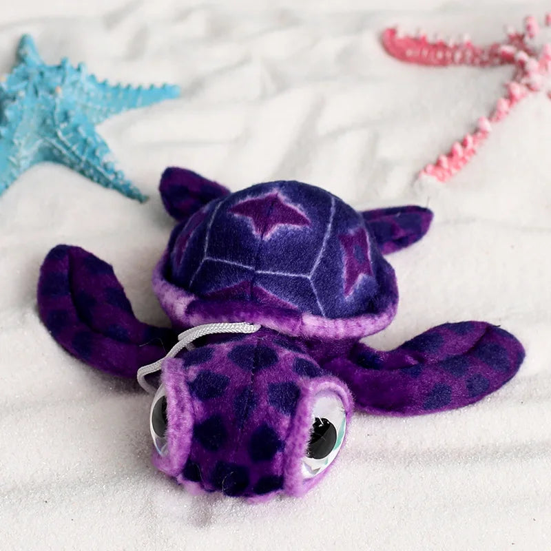 Peluche tortue mignonne violette sur du sable fin