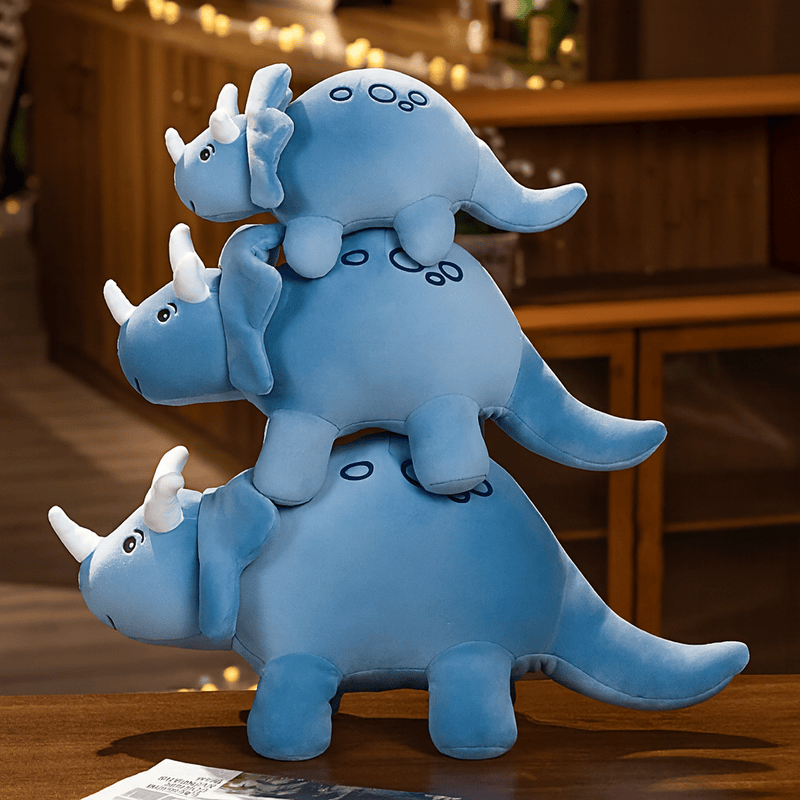 Trois peluches triceratops bleues sur une table 