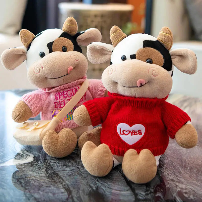 Deux peluches vaches avec un col roulé sur une table
