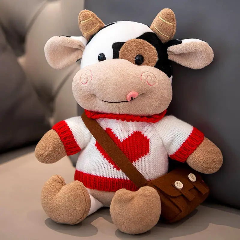 Peluche vache avec son col roulé blanc avec un coeur sur un canapé