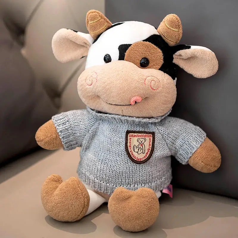 Peluche vache avec son col roulé gris sur un canapé
