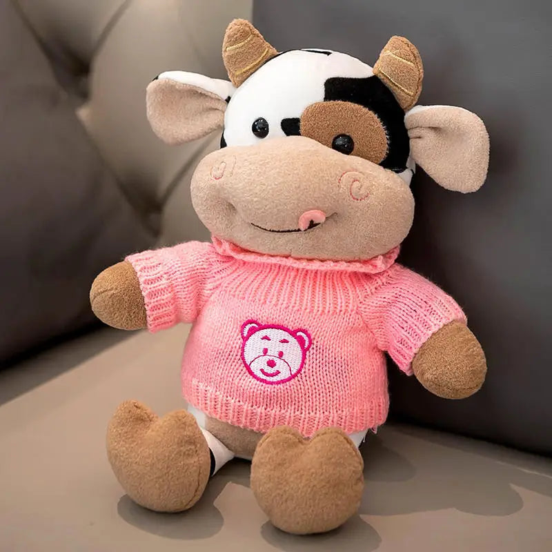 Peluche vache avec son col roulé rose sur un canapé