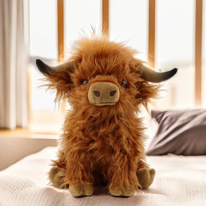 Peluche vache highland sur un lit