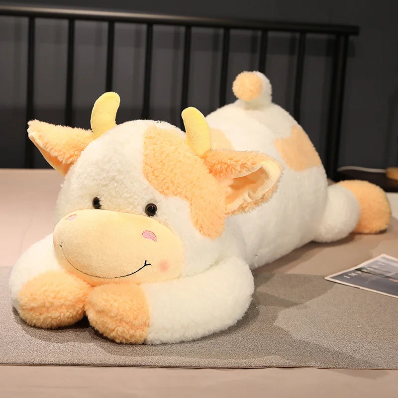 Peluche vache xxl jaune et blanche sur un lit