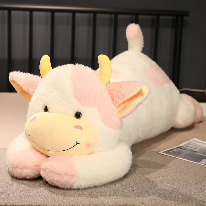 Peluche vache xxl rose et blanche sur un lit