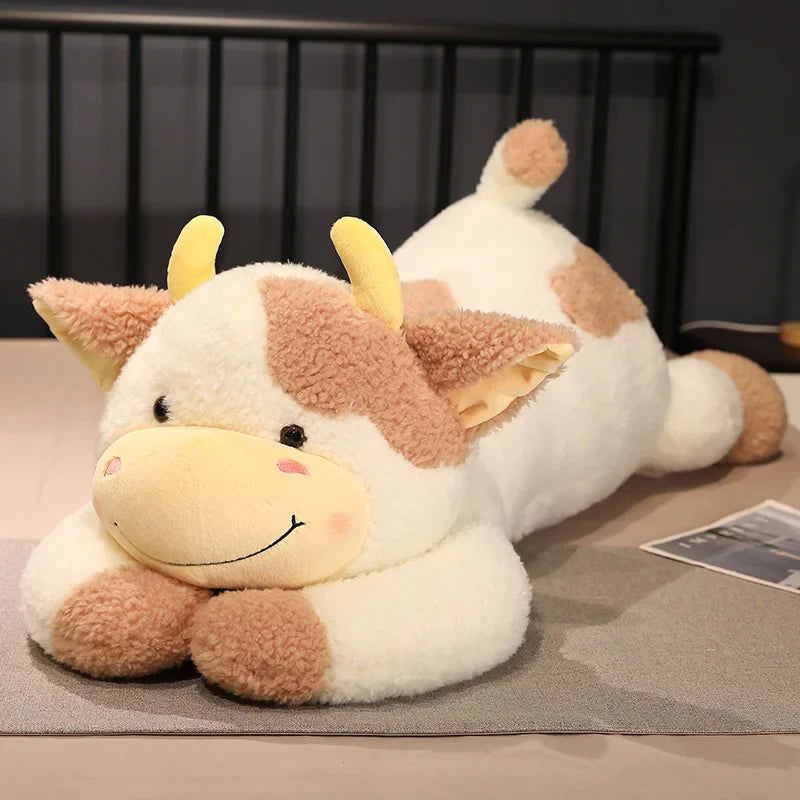 Peluche vache xxl brune et blanche sur un lit 