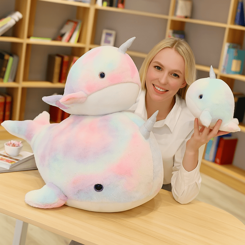 Trois peluches baleines licorne sur une table tenue par une femme