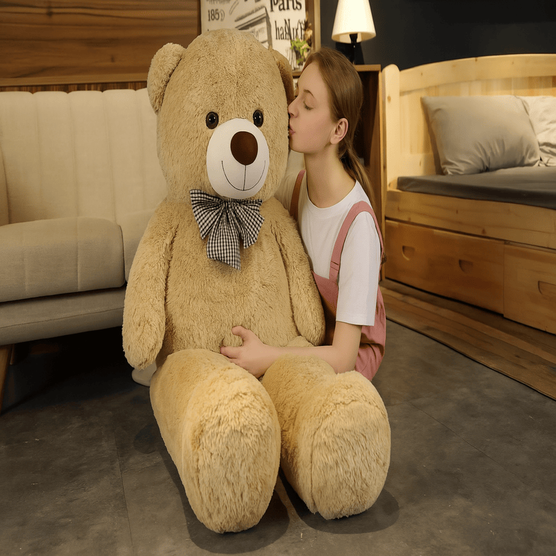ours beige en peluche géante avec noeud papillon dans les bras d'une fille